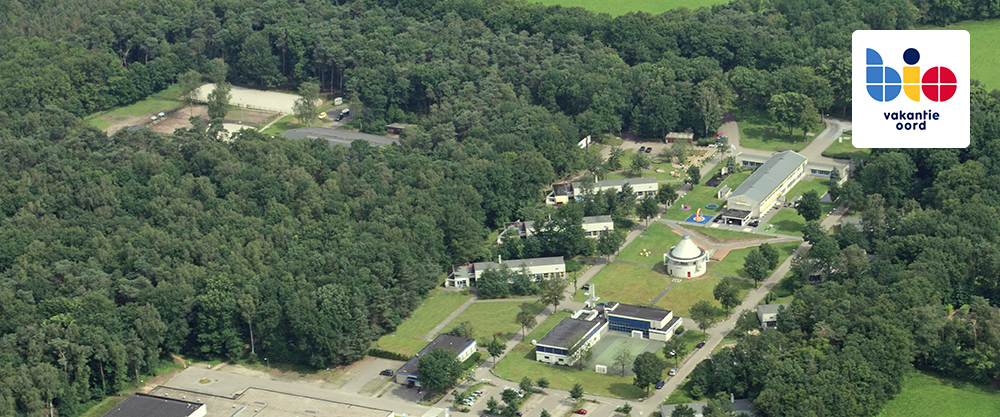 Luchtfoto van Bio Vakantieoord, gelegen in een bosrijke omgeving met diverse gebouwen en faciliteiten voor gezinnen met een zorgintensief kind.